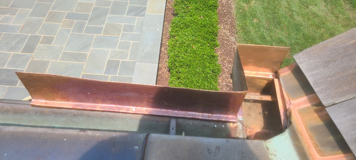 Custom copper flashing fitted along a bluestone patio edge