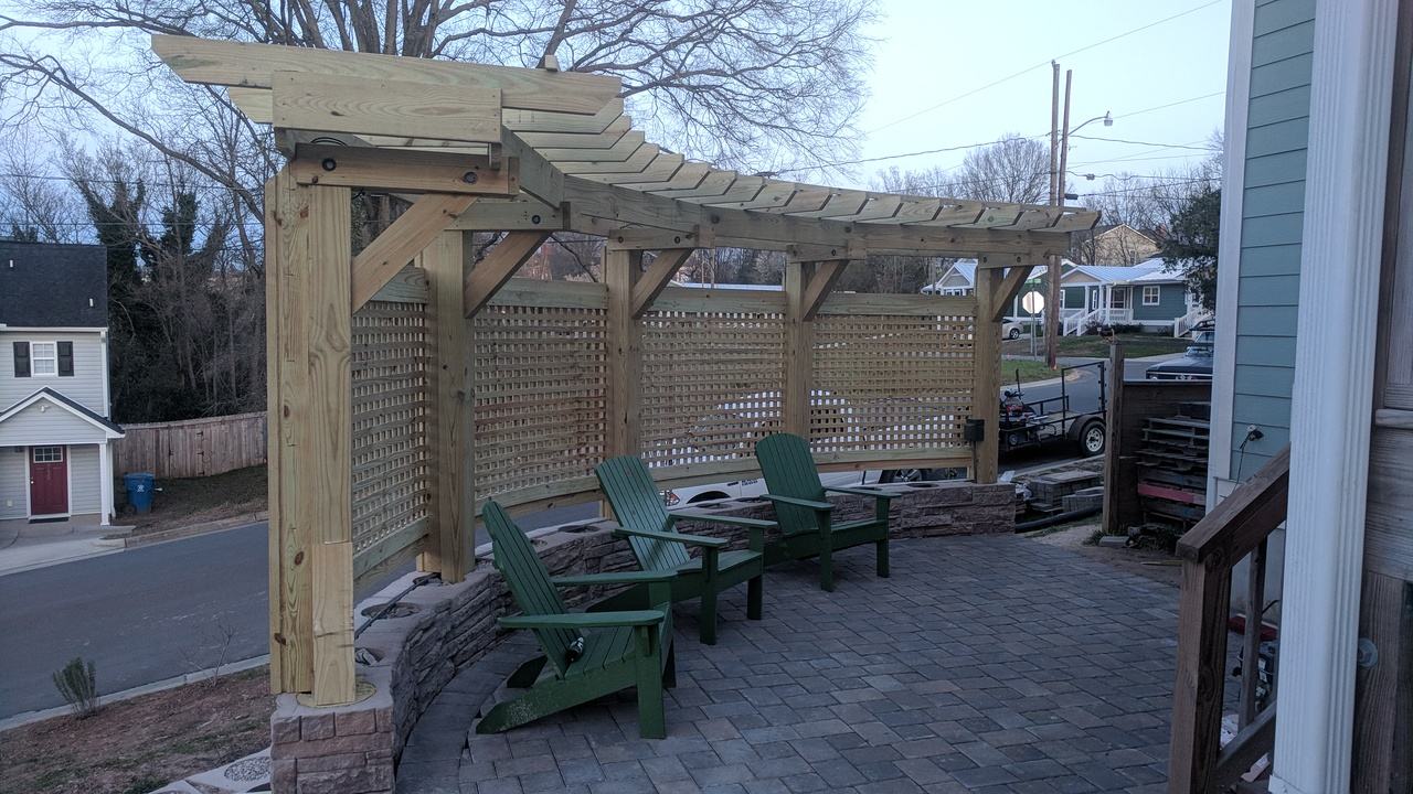 Cedar pergola with privacy screen over a paver patio with Adirondack chairs