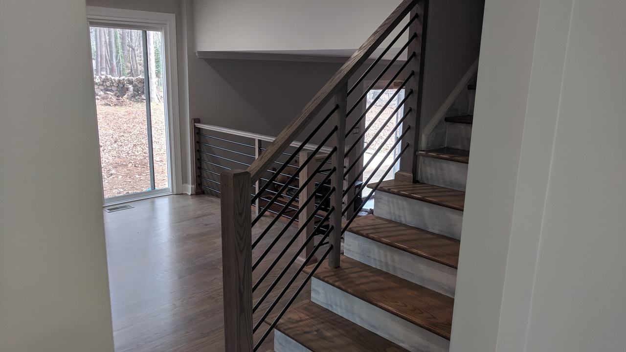 Staircase with wood treads and a modern black horizontal-bar railing