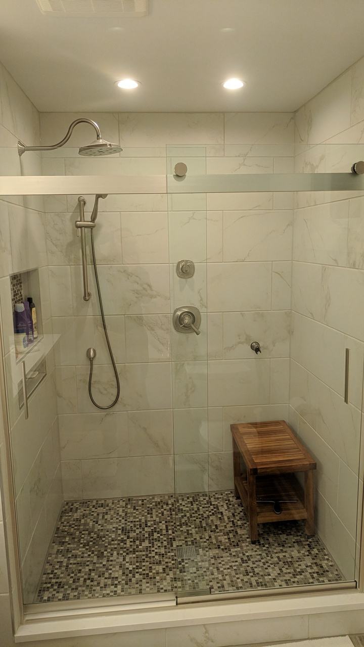 Tiled shower with wood-look plank tile, built-in niches and a glass door